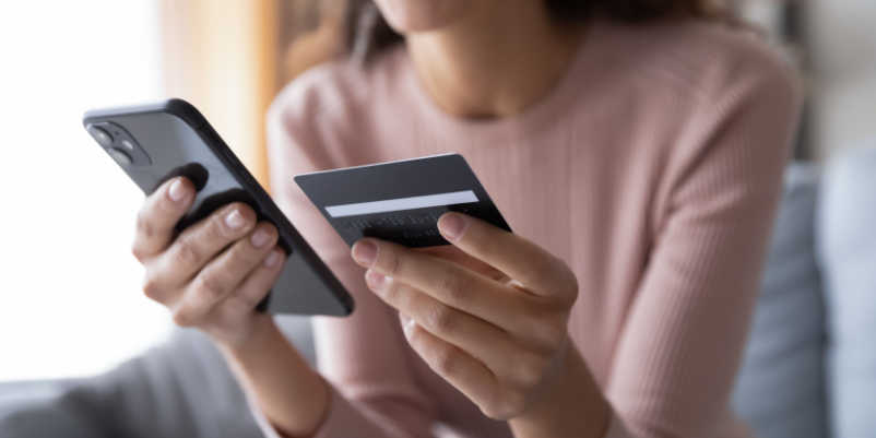 スマホとクレジットカードを持っている女性